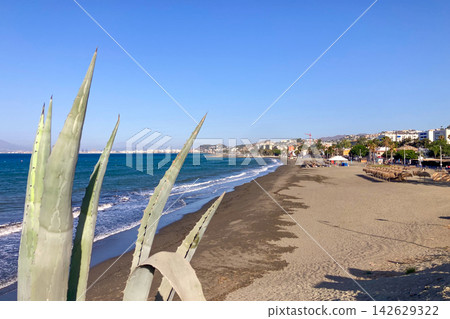 Golden sunrise light illuminates beach creating a peaceful Mediterranean seascape with gentle waves and rugged coastal scenery in Malaga, Spain Golden sunrise light illuminates beach creating a peaceful Mediterranean seascape with gentle waves and rugged coastal scenery in Malaga, Spain 142629322