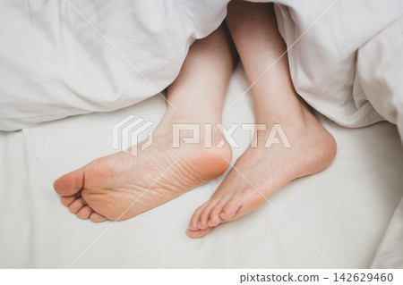 Women's feet lying on the bed Women's feet lying on the bed 142629460