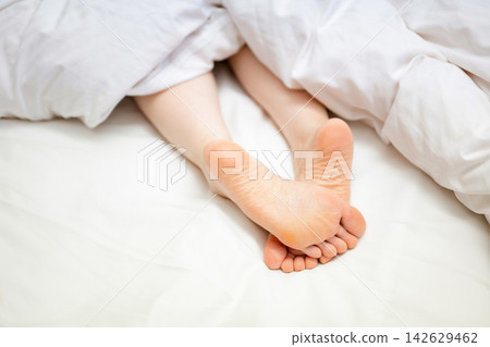Women's feet lying on the bed Women's feet lying on the bed 142629462
