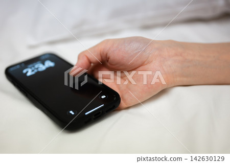 A woman with a smartphone in bed 142630129