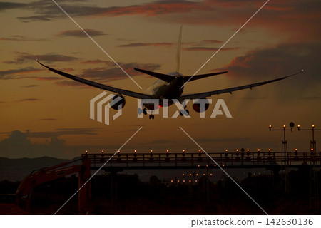 一架大型噴射客機沿著引導燈的軌跡,緩緩降落在夕陽的天空中。 一架大型噴射客機沿著引導燈的軌跡,緩緩降落在夕陽的天空中。 142630136