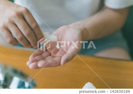 A 40-year-old man pours lotion from the bottle into his palm as part of his men's skincare routine. A 40-year-old man pours lotion from the bottle into his palm as part of his men's skincare routine. 142630189