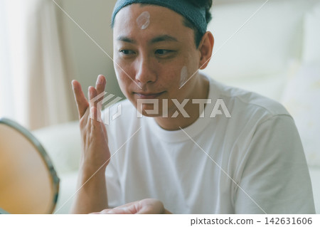 一位四十多歲男士的美容秘訣:用手指仔細塗抹潤膚露。 一位四十多歲男士的美容秘訣:用手指仔細塗抹潤膚露。 142631606