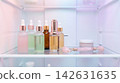 Luxurious cosmetic advertising concept featuring glass dropper bottles and facial tools cooling on a modern refrigerator shelf with soft pastel light 142631635