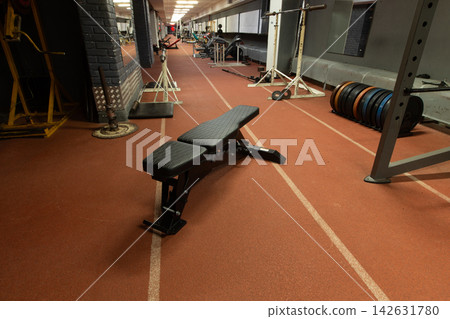 Empty weight bench in a gym space during early morning hours with exercise equipment in the background Empty weight bench in a gym space during early morning hours with exercise equipment in the background 142631780