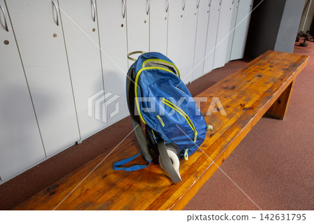 Backpack rests on a wooden bench in a locker room after a workout session in a gym setting Backpack rests on a wooden bench in a locker room after a workout session in a gym setting 142631795