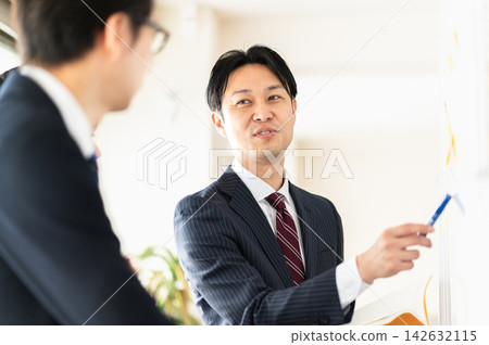 三個身穿西裝的男人正在開會,他們面帶微笑,使用著白板。 三個身穿西裝的男人正在開會,他們面帶微笑,使用著白板。 142632115