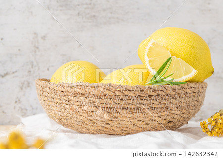 Fresh yellow lemons with rosemary sprigs in basket Fresh yellow lemons with rosemary sprigs in basket 142632342