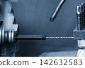 Small deep hole drilling process on a nylon shaft part using a lathe machine in blue tone 142632583