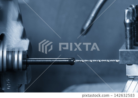 Small deep hole drilling process on a nylon shaft part using a lathe machine in blue tone Small deep hole drilling process on a nylon shaft part using a lathe machine in blue tone 142632583