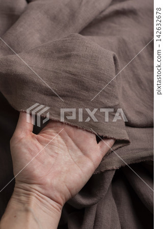 Hand Holding Chocolate Brown Linen Fabric Edge Hand Holding Chocolate Brown Linen Fabric Edge 142632678