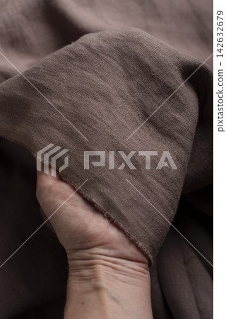 Hand Holding Chocolate Brown Linen Fabric Edge Hand Holding Chocolate Brown Linen Fabric Edge 142632679