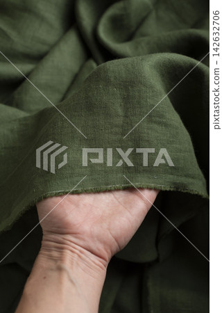Hand Holding Olive Green Linen Fabric Edge Hand Holding Olive Green Linen Fabric Edge 142632706
