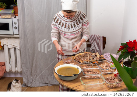 In a cozy home setting, a woman prepares kholodets, aspic, or jellied meat, traditional Ukraine dish, by packing cooked meat into glass dishes In a cozy home setting, a woman prepares kholodets, aspic, or jellied meat, traditional Ukraine dish, by packing cooked meat into glass dishes 142633267