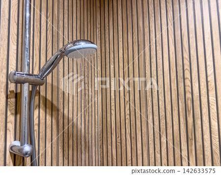 Running shower water from chrome handheld showerhead, plumbing installation, hygiene, bathroom repair, interior service. Running shower water from chrome handheld showerhead, plumbing installation, hygiene, bathroom repair, interior service. 142633575