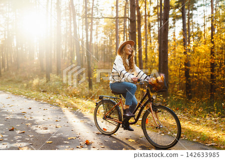 Beautiful woman in stylish clothes with bicycle walking in autumn park Woman walking in sunny forest Beautiful woman in stylish clothes with bicycle walking in autumn park Woman walking in sunny forest 142633985