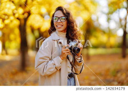 Beautiful woman taking pictures in the autumn forest. Rest, relaxation, tourism, lifestyle concept. 142634179