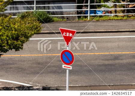 A "Stop" sign (an inverted triangle) and a "No Parking" traffic sign stand by the side of the road. A "Stop" sign (an inverted triangle) and a "No Parking" traffic sign stand by the side of the road. 142634517