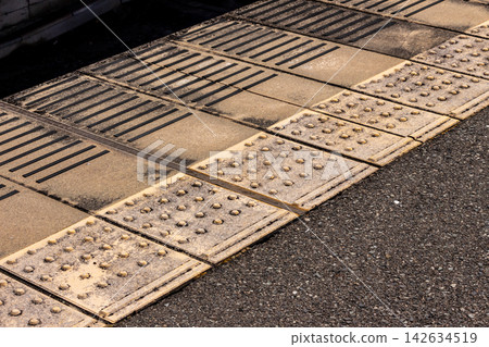 A diagonal angle shot of the footing on a station platform where tactile paving and linear blocks for the visually impaired are laid. A diagonal angle shot of the footing on a station platform where tactile paving and linear blocks for the visually impaired are laid. 142634519