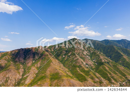 Aerial landscape of a rugged mountain range with green slopes 142634844