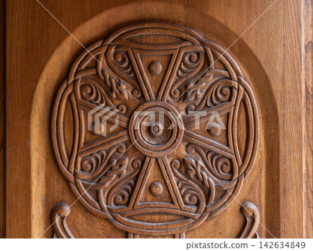 Ornate carved wooden medallion panel featuring a circular cross Ornate carved wooden medallion panel featuring a circular cross 142634849