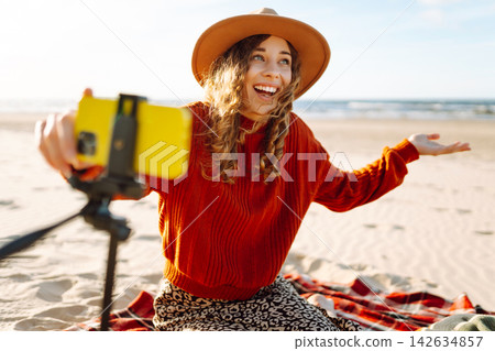 Style woman using smartphone with stabilizer, taking pictures in on sea beach. Woman creates content Style woman using smartphone with stabilizer, taking pictures in on sea beach. Woman creates content 142634857