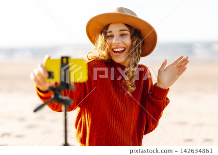 Style woman using smartphone with stabilizer, taking pictures in on sea beach. Woman creates content Style woman using smartphone with stabilizer, taking pictures in on sea beach. Woman creates content 142634861