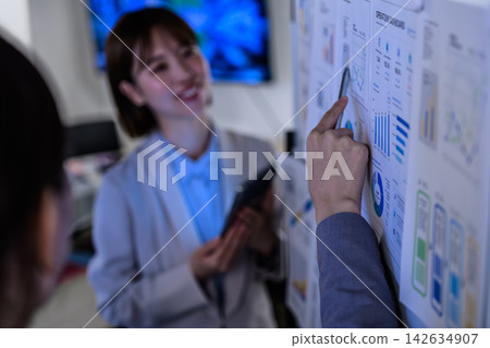 一隻手指向圖表,一位微笑的女士 一隻手指向圖表,一位微笑的女士 142634907