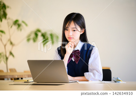一位女學生正在用筆記型電腦學習,臉上表情嚴肅。 一位女學生正在用筆記型電腦學習,臉上表情嚴肅。 142634910
