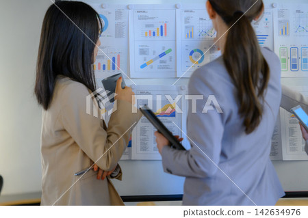 兩名女子正在查看白板上的文件。 兩名女子正在查看白板上的文件。 142634976