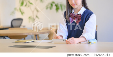 一名高中女生在學習時用智慧型手機找資料。 一名高中女生在學習時用智慧型手機找資料。 142635014