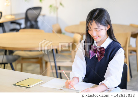 A high school girl studying for entrance exams, writing in her notebook at her desk. A high school girl studying for entrance exams, writing in her notebook at her desk. 142635038