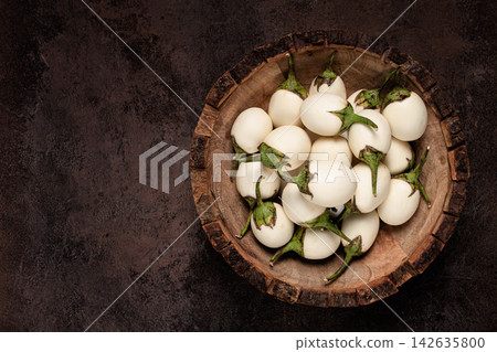 white mini eggplant, in a wooden bowl, on the table, close-up. white mini eggplant, in a wooden bowl, on the table, close-up. 142635800
