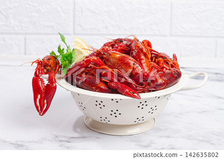 Freshly cooked crawfish in a colander on a white marble surface with green herbs Freshly cooked crawfish in a colander on a white marble surface with green herbs 142635802