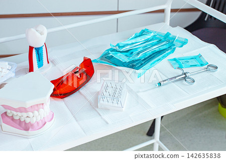 Various instruments, dental models, and hygiene items are laid out on the table in the dental office. natural light Various instruments, dental models, and hygiene items are laid out on the table in the dental office. natural light 142635838