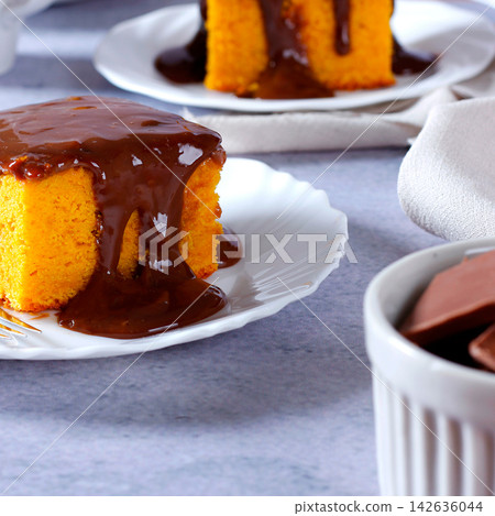 Moist Brazilian carrot cake topped with creamy chocolate, served on a white plate. Moist Brazilian carrot cake topped with creamy chocolate, served on a white plate. 142636044