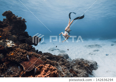 Beauty woman freediver dives above a coral reef in a clear tropical sea 142636294