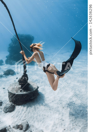 Free diver woman holding a rope while exploring a coral reef underwater Free diver woman holding a rope while exploring a coral reef underwater 142636296