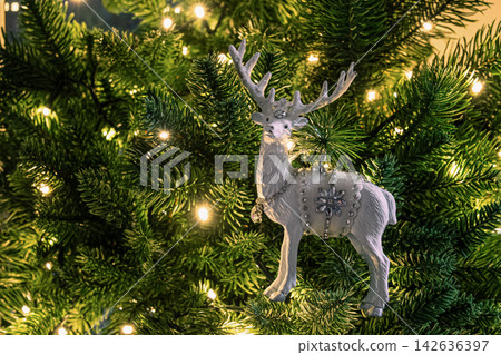 White reindeer ornament on illuminated Christmas tree White reindeer ornament on illuminated Christmas tree 142636397