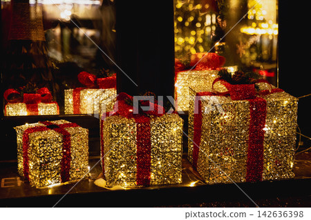 Glowing Christmas gift boxes with red ribbons at night Glowing Christmas gift boxes with red ribbons at night 142636398