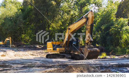 Yellow excavators machine on construction site. Heavy equipment works on a construction site. Industrial machinery concept, earthmoving work Yellow excavators machine on construction site. Heavy equipment works on a construction site. Industrial machinery concept, earthmoving work 142636901