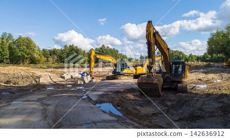 Crawler excavators level the ground at a construction site for a building under construction. Crawler excavators level the ground at a construction site for a building under construction. 142636912
