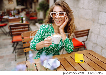 Young woman tourist drinks coffee in the old town in summer trip. Travel and vacations Young woman tourist drinks coffee in the old town in summer trip. Travel and vacations 142636952