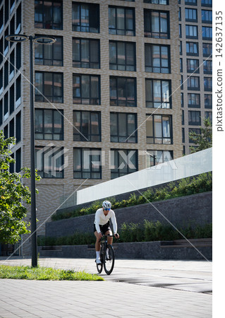 Road cyclist riding through modern urban neighborhood Road cyclist riding through modern urban neighborhood 142637135