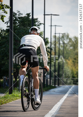 Male road cyclist riding away on bike path Male road cyclist riding away on bike path 142637137