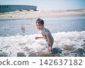 A boy laughing, his clothes still wet at the water's edge of the summer sea. 142637182