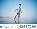 A boy playing in the sand at the water's edge of the beach in summer. 142637190