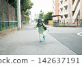 A boy running through a residential street with a hat and backpack, smiling. 142637191