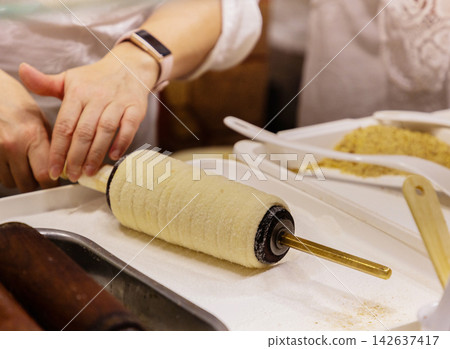 Hands preparing traditional pastry on rolling pin with ingredients nearby Hands preparing traditional pastry on rolling pin with ingredients nearby 142637417
