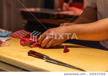 Skilled chef slicing fresh fish on wooden cutting board in kitchen Skilled chef slicing fresh fish on wooden cutting board in kitchen 142637438